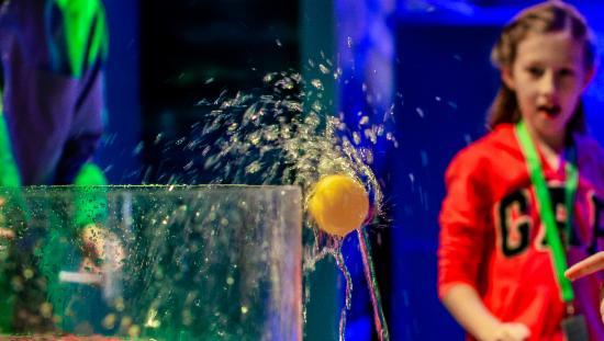 Bildet viser ne jente som kaster en gul ball i en beholder med vann